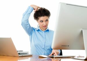 Woman starting at computer screen and scratching her head